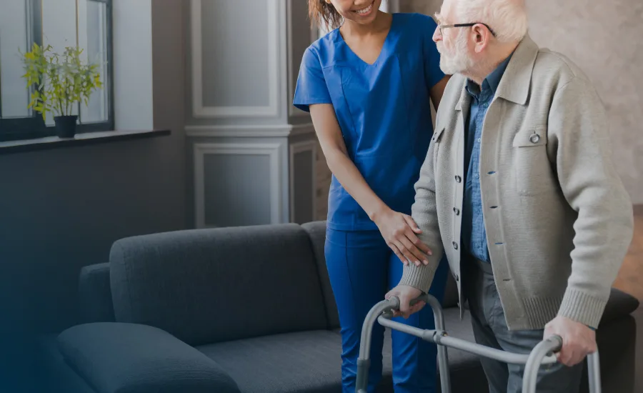 An elderly man walks with a nurse in a bright room, highlighting support and companionship in healthcare