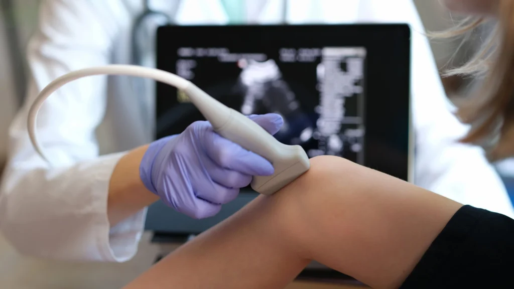 A healthcare professional operates an ultrasound machine to examine a patient's knee for diagnostic purposes ultrasound guided injection Birmingham