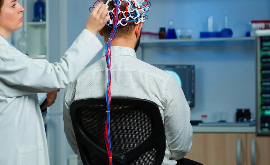 A man in a lab coat sits at a computer, engaged in neurological therapy research or analysis shockwave therapy clinic UK