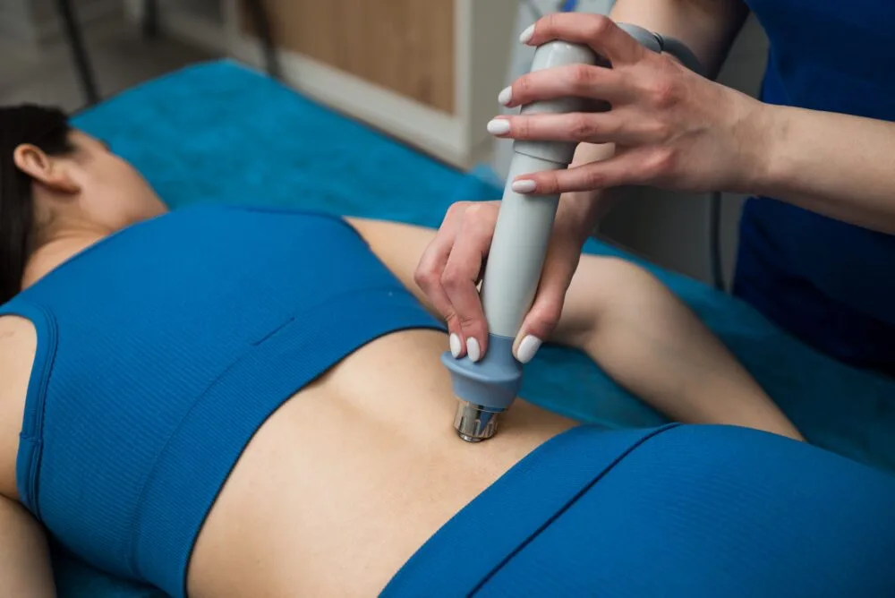 Healthcare practitioner applying extracorporeal shockwave therapy to a patient's painful muscle tissue using a handheld transducer device best shockwave therapy in Birmingham