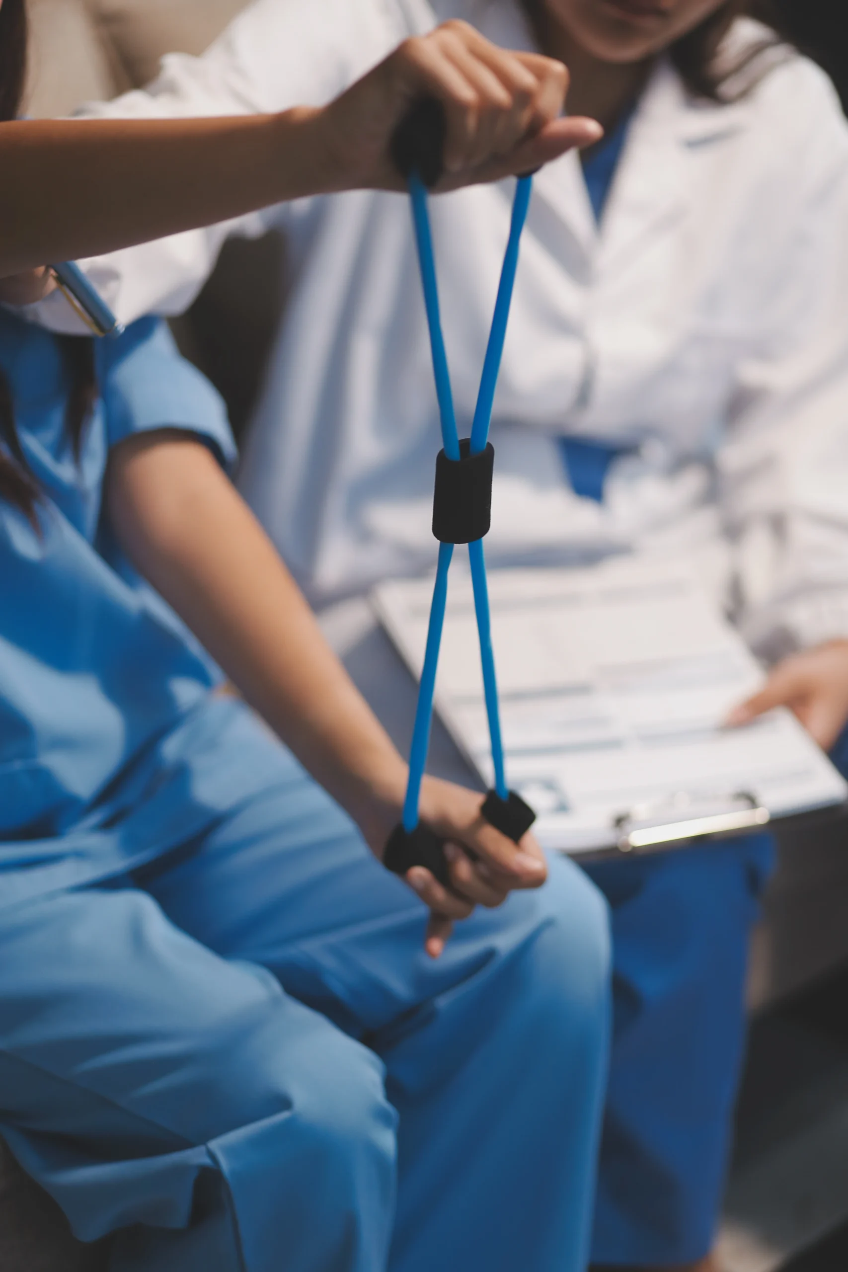 A woman presents a blue strap to a patient, suggesting a discussion or demonstration related to medical equipment physiotherapy clinic in Selly Oak